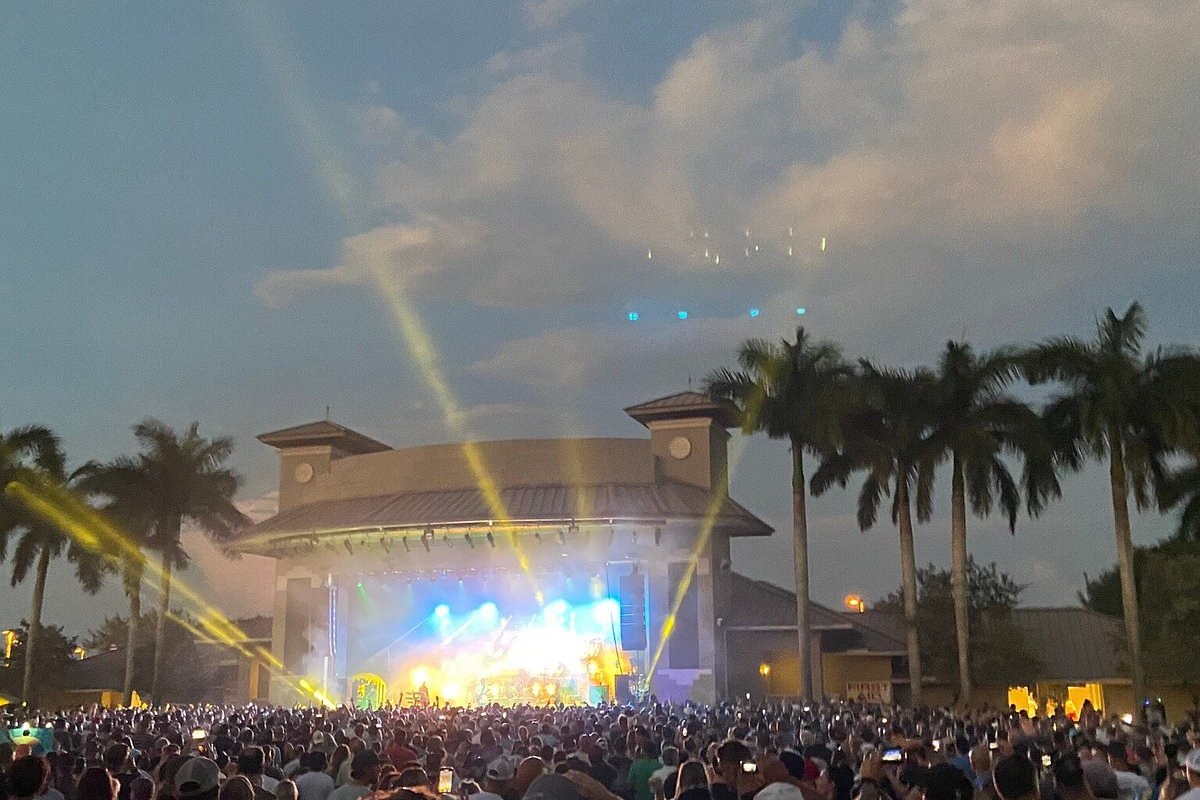 The Sunset Cove stage lit up after dark, beams over the palms and the lawn